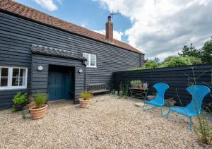 a backyard with two blue chairs and a house at The Hayloft in Dilham