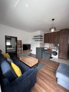 een woonkamer met een blauwe bank en een keuken bij Oasis Royal Apartments in Sarajevo