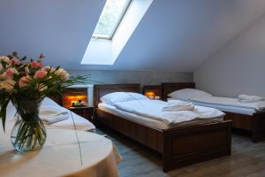 sypialnia z dwoma łóżkami i wazonem kwiatów na stole w obiekcie Resort Pod Lasem w mieście Kolonowskie