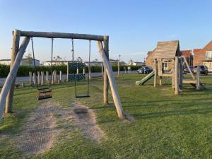 a playground with a swing set in the grass at Spoonbill Cottage in Filey