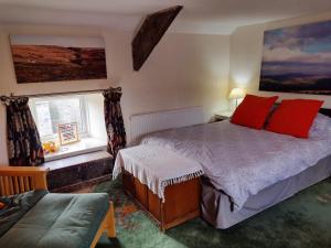 a bedroom with two beds with red pillows and a window at Black Dog House in Bishop Auckland