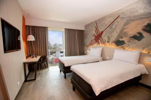 um quarto de hotel com duas camas e uma secretária em ibis Styles Lima Benavides Miraflores em Lima