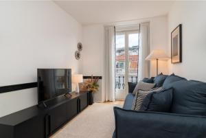 uma sala de estar com um sofá azul e uma televisão em Ando Living - Santa Justa 77 Flats em Lisboa