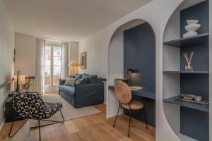 uma sala de estar com um sofá azul e cadeiras em Ando Living - Santa Justa 77 Flats em Lisboa