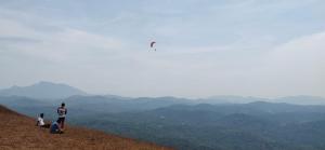 a group of people standing on a hill flying a kite at StoneAge Resort Sakleshpur in Sakleshpur