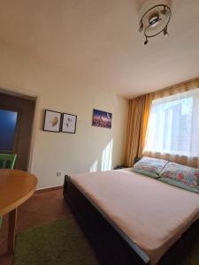sypialnia z łóżkiem z oknem i stołem w obiekcie Sinemorets apartment w mieście Sinemorec