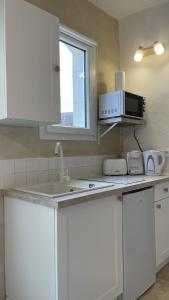 uma cozinha com armários brancos e um micro-ondas em Insolite : Gîte Namaste à 500m à pied du Zoo de Beauval em Seigy