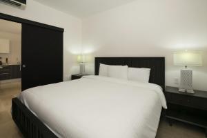 a bedroom with a large white bed with a black headboard at Roble Sabana 304 Luxury Apartment - Reserva Conchal in Playa Conchal