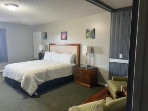 a hotel room with a bed and a chair at Vacationland Inn & Suites in Brewer +8 photos