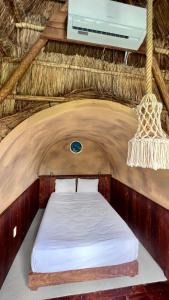 uma cama num quarto com telhado de palha e tecto em Pepos Xul-Ha em Xul-Ha