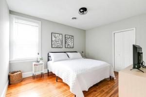 ein weißes Schlafzimmer mit einem Bett und einem TV in der Unterkunft Private Boho Bungalow 10 Minutes to Downtown RVA! in Richmond