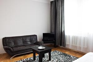 Hotel Sofiivka في Konopnitsa: غرفة معيشة مع أريكة جلدية سوداء وطاولة