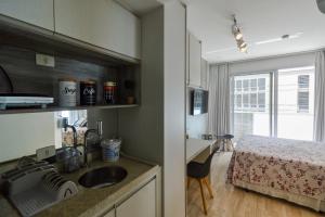 a kitchen with a sink and a room with a bed at Loft Downtown São Luis, 612 in Sao Paulo