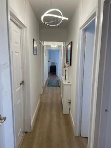 a hallway with a long corridor with white walls and wood floors at Great Location 4 bedroom in London