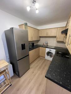 La cuisine est équipée d'un réfrigérateur en acier inoxydable et de placards en bois. dans l'établissement Great Location 4 bedroom, à Londres
