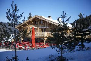 a log house with red umbrellas in front of it at Le Lodge Chasse Montagne in Les Gets