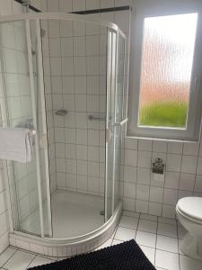 een badkamer met een douche, een toilet en een raam bij Ferienwohnung Nähe Hannover Messe in Hannover