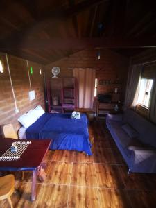 a bedroom with a bed and a couch and a table at Chalé Astral in Alto Paraíso de Goiás