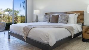 1 dormitorio con 1 cama grande y balcón en Bougainvillea 2102 Luxury Apartment - Reserva Conchal, en Playa Conchal