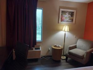 um quarto com uma cama, uma cadeira e uma janela em Fairway Inn La Porte em La Porte