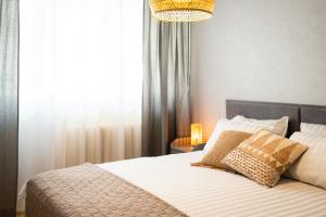 a bed with two pillows and a chandelier in a bedroom at Leola Center Apartment in Viljandi