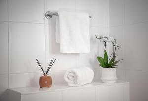 a white bathroom with a towel and flowers on a shelf at Gästehaus zum roten Hahn in Lüneburg