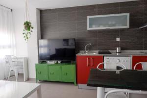 cocina con armarios rojos y verdes y TV en Apartamentos Vernia, en Xàtiva