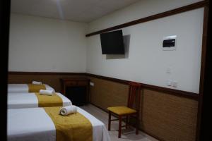 a room with three beds and a flat screen tv at Hostal La Conileña in Conil de la Frontera