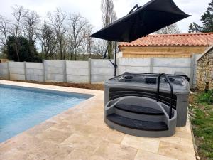 een grill met een parasol naast een zwembad bij GITE ENTRE TERRE ET MER in Mareuil-sur-Lay