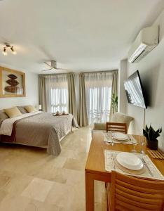 a bedroom with a bed and a table and a dining room at Ivory Suites in Málaga