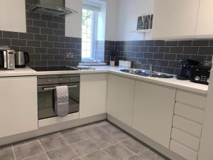 a kitchen with white cabinets and a sink at Purdis Farm - Flat 4 in Bucklesham