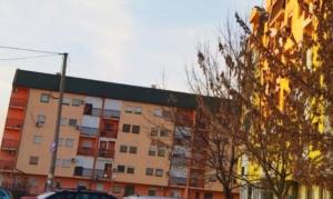 un gran edificio de apartamentos con coches aparcados frente a él en Apartman Lada, en Bijeljina
