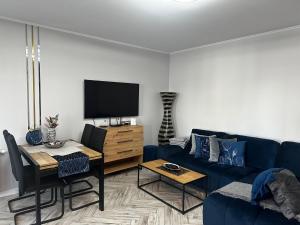a living room with a blue couch and a tv at Apartament Elisabeth BLUE I in Pogórze