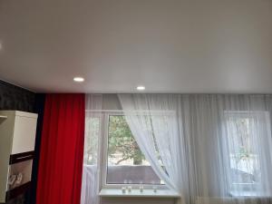 a window with white curtains and red curtains at MilaAna in Visaginas +35 photos