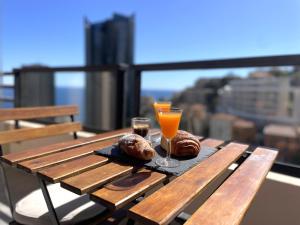 einen Holztisch mit zwei Backwaren und einem Glas Orangensaft in der Unterkunft NEW Studio, piscine et vue mer • proche de Monaco in Beausoleil