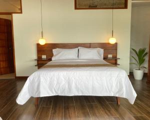 a bedroom with a large white bed with two lights at Riosol Hotel Laguna Azul in Sauce