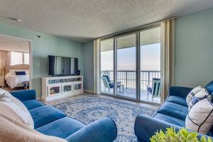 sala de estar con sofá azul y TV en Pensacola Beach Vacation Rental with Private Balcony, en Gulf Breeze