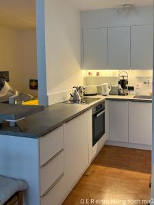 - une cuisine avec des placards blancs et un évier dans l'établissement Apartment mit Blick auf das Eversten Holz 42qm, à Oldenbourg