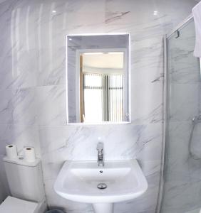 黑潭的住宿－Blackpool Resort Hotel，白色的浴室设有水槽和镜子