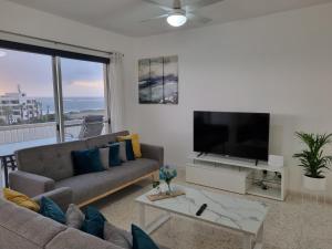 a living room with a couch and a flat screen tv at Diamond Sea View Penthouse in Paphos
