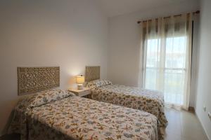 Dos camas en una habitación de hotel con ventana. en Exclusivo Adosado en Punta Coral El Rompido, en El Rompido 17 fotos más
