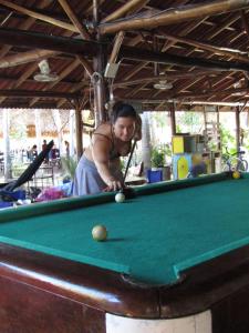 a woman is playing a game of pool at Hotel Restaurante Spa La Barca de Oro in Las Peñitas