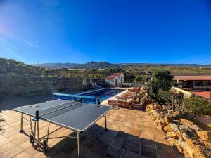 a ping pong table on a patio with a pool at Exquisite rural house with garden, pool and sea views in Arico Viejo