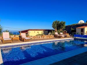 a swimming pool with chairs and a house at Exquisite rural house with garden, pool and sea views in Arico Viejo