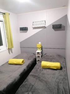 - 2 lits dans une chambre avec des oreillers jaunes dans l'établissement Mobil-Home Cosy Climatisé 3 chambres, à Vic-la-Gardiole