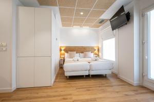 um quarto com uma cama branca e uma televisão em Elegant Rooms Lasarte em Lasarte