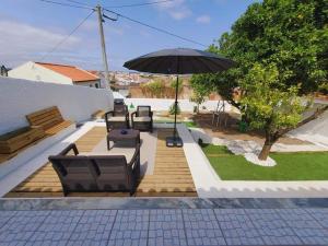 patio z parasolem, krzesłami i stołem w obiekcie A casa da Laranjeira w mieście Vale Covo