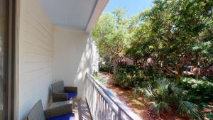 a balcony with two chairs and a garden at Villas by The Sea Three Bedroom Apartment in Jekyll Island