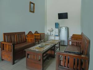 Zimmer mit einem Tisch, Stühlen und einem Kühlschrank in der Unterkunft OYO 92377 Wisma Melyro Syariah 