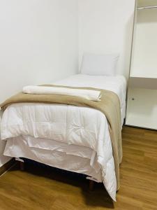 a white bed in a room with a wooden floor at Hotel Santorine Plaza - By UP Hotel in Itabira